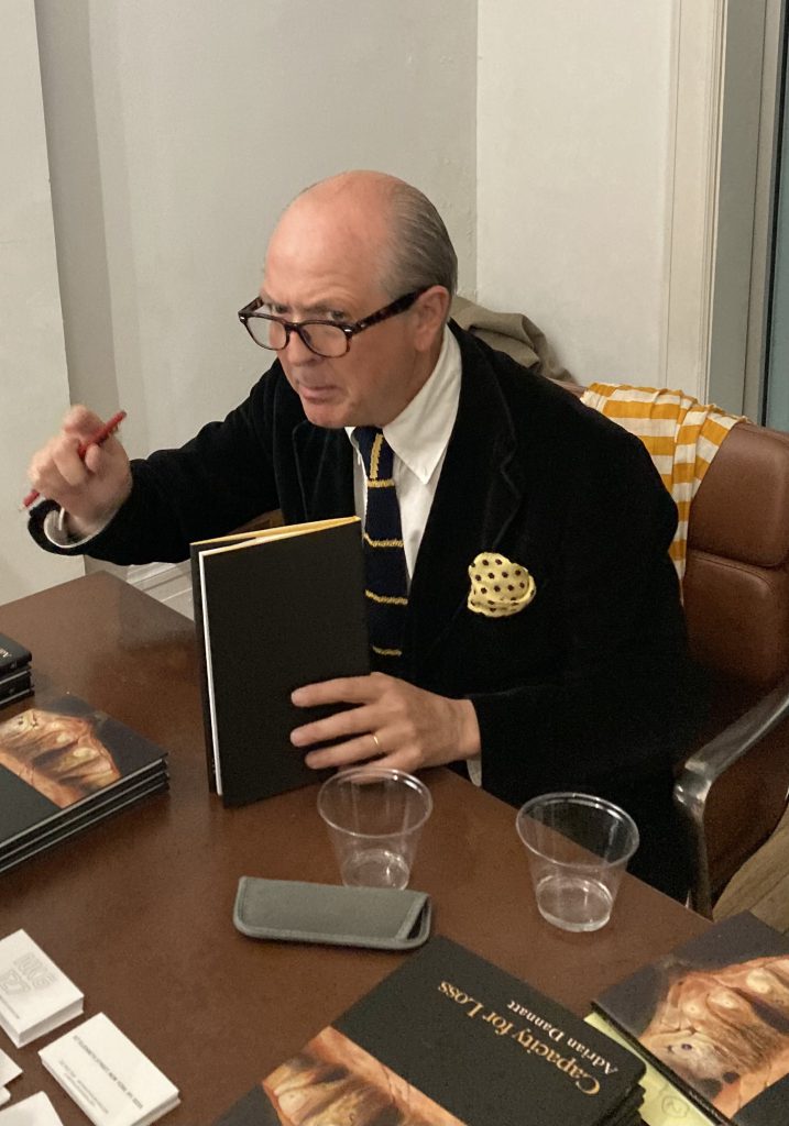 poet Adrian Dannatt gestures after signing a copy of his collection of poetry, Capacity for Loss. It's a pretty good book