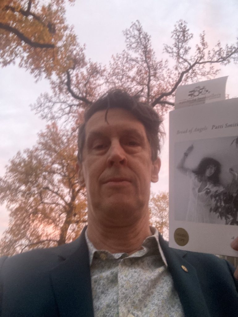 person holding a copy of Bread of Angels by Oatti Smith on an autumn afternoon 
